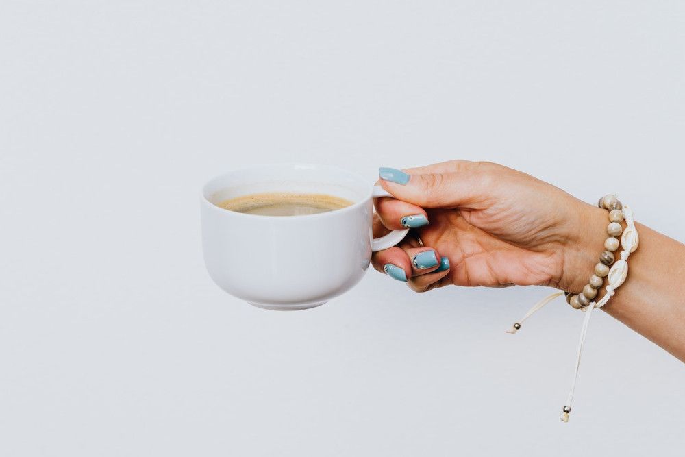 Eine weibliche Hand hält eine Kaffeetasse