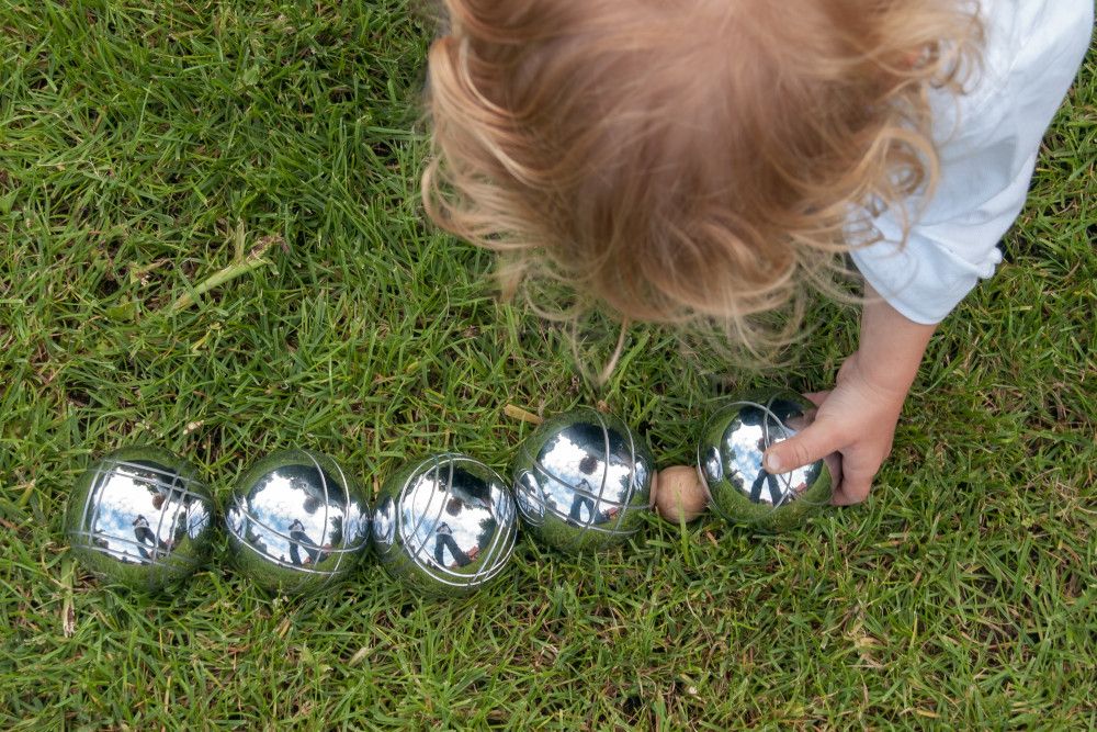 Ein Kind mit Metallkugeln aus dem Pétanquespiel