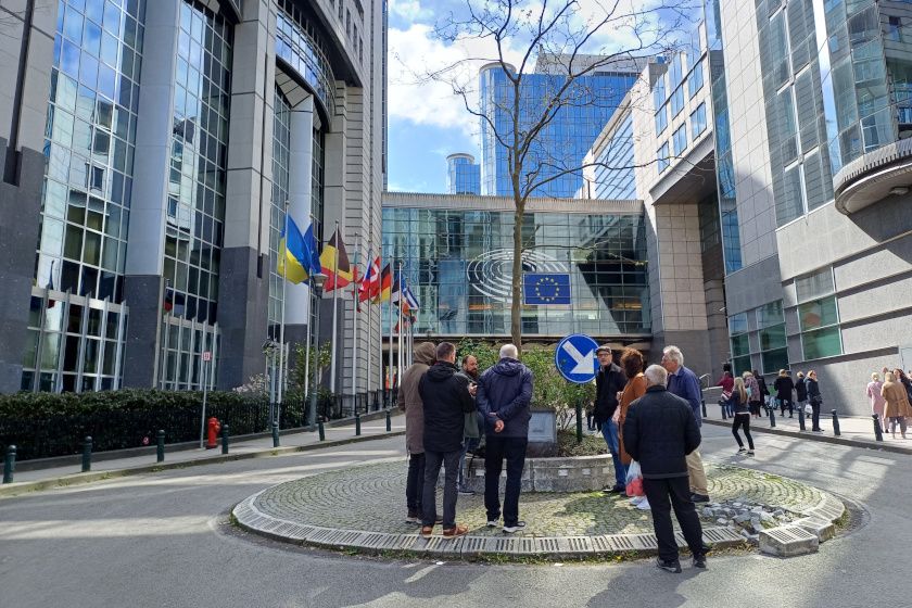 Eine kleine Besuchergruppe vor einer grossen Bürofassade mit der Europaflagge.