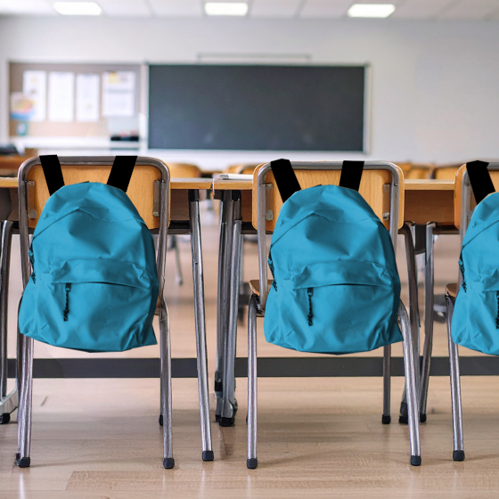 Ein Klassenzimmer. Auf den Stühlen identische Rucksäcke